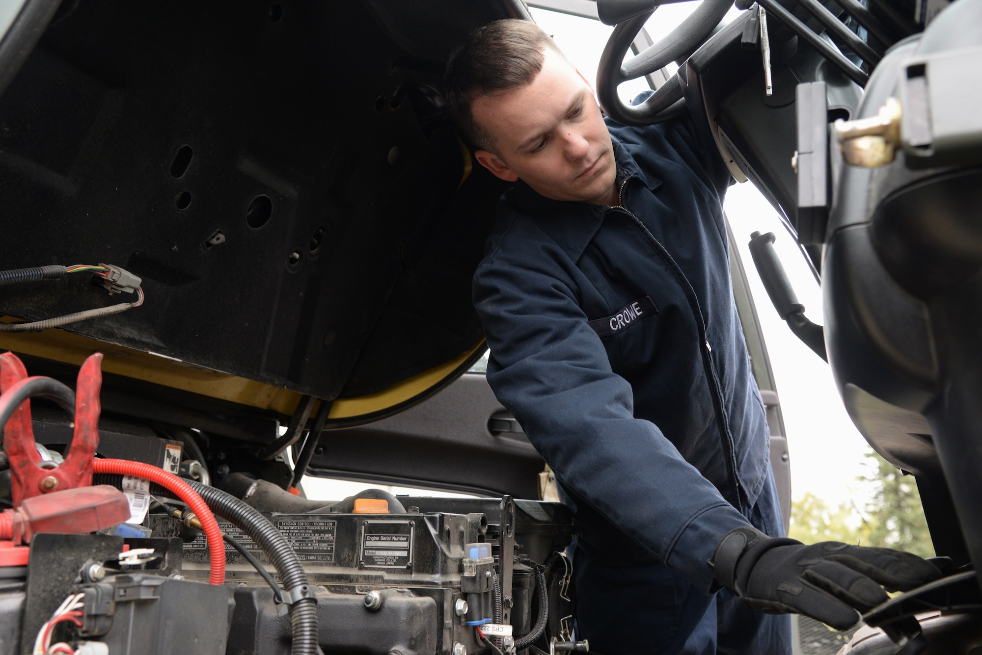 U.S. Air Force Senior Airman Blake Crowe, a 354th Logistics Readiness Squadron vehicle maintenance journeyman, pushes the pedal of a forklift to try and start it, Aug. 31, 2015, at Eielson Air Force Base, Alaska. Crowe used jumper cables to get the expended battery running again. (U.S. Air Force photo by Airman 1st Class Cassandra Whitman/Released)