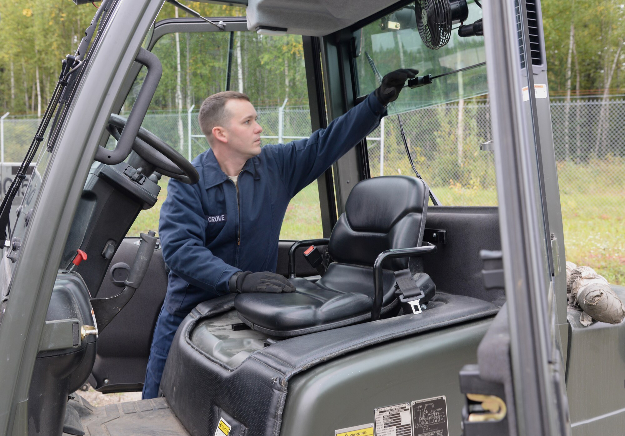 U.S. Air Force Senior Airman Blake Crowe, a 354th Logistics Readiness Squadron vehicle maintenance journeyman, uses a system of maneuvers that opens the seat and reveals the engine and battery of a forklift, Aug. 31, 2015, at Eielson Air Force Base, Alaska. Crowe needed to jumpstart the forklift with an expended battery to get the vehicle running again. (U.S. Air Force photo by Airman 1st Class Cassandra Whitman/Released)
