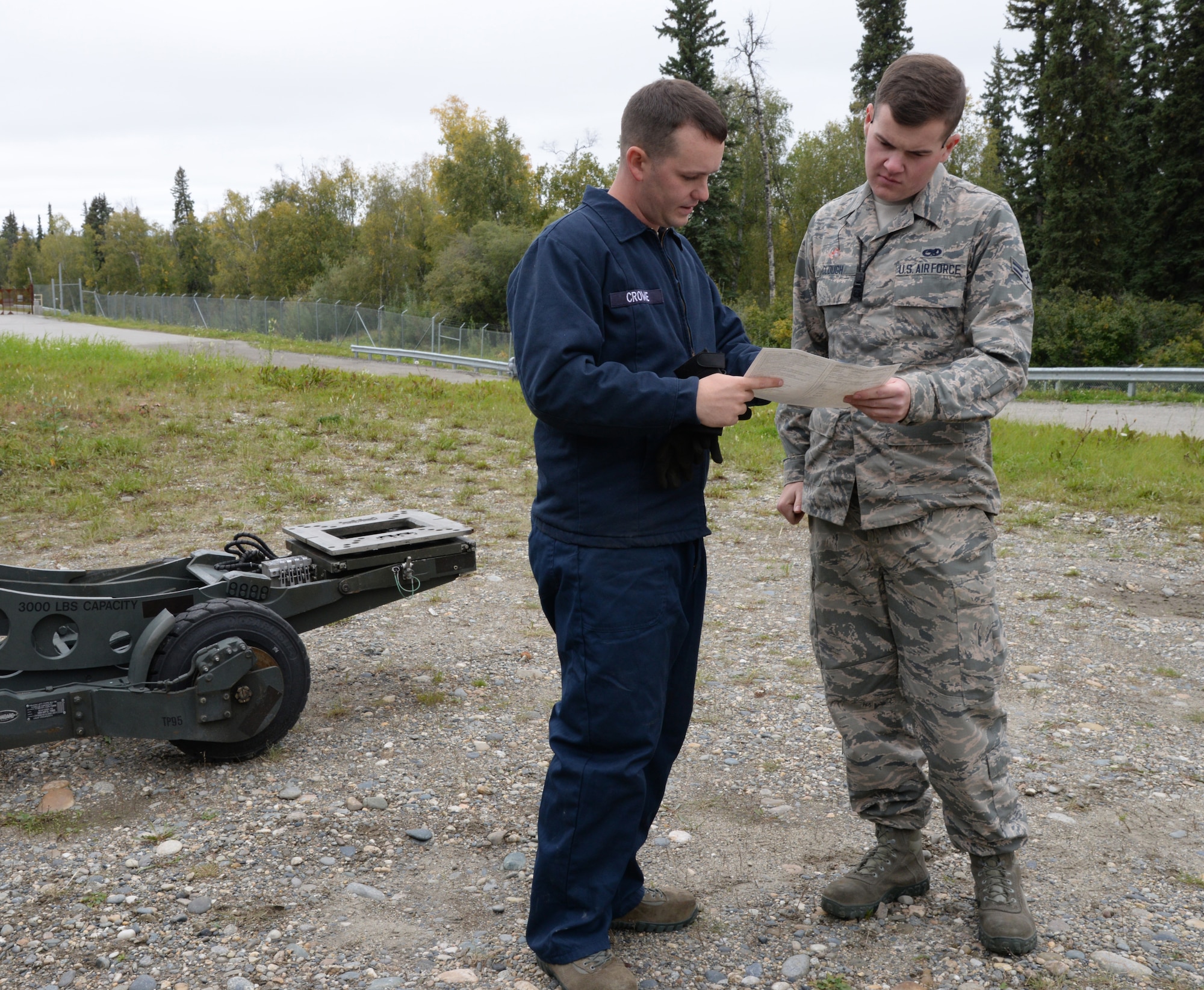 U.S. Air Force Senior Airman Blake Crowe, a 354th Logistics Readiness Squadron vehicle maintenance journeyman, asks Airman 1st Class Hayden Clough, a 354th Maintenance Squadron munitions crew member, to sign an AF Form 1800, describing the maintenance completed on Aug. 31, 2015, at Eielson Air Force Base, Alaska. The AF1800 is used to record when maintenance is performed on a vehicle as well as to ensure daily checks are done. (U.S. Air Force photo by Airman 1st Class Cassandra Whitman/Released)