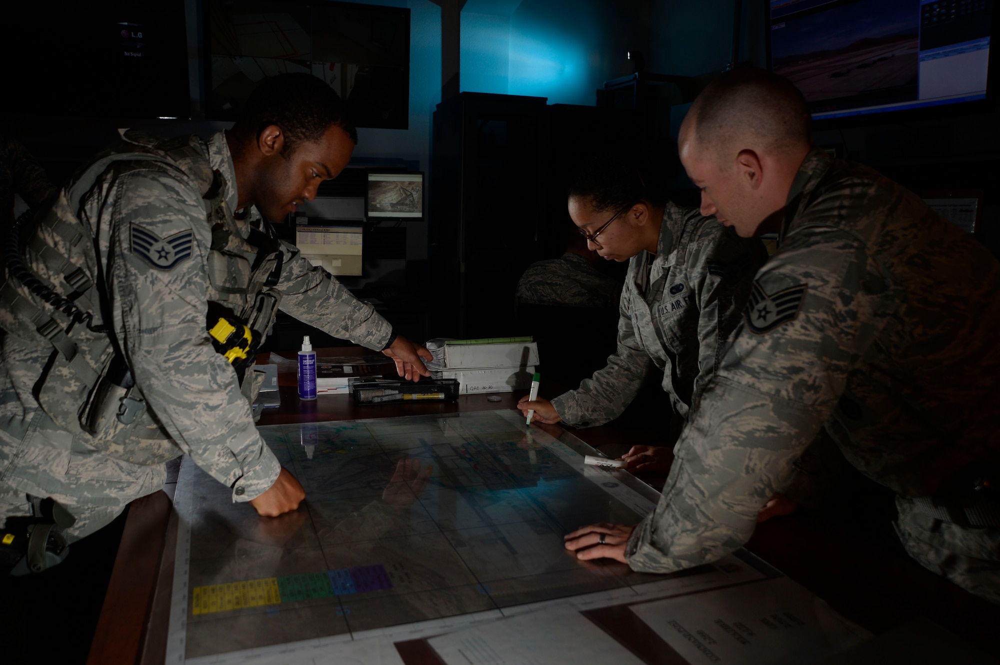 Staff Sgt. Kevin Singleton, 799th Security Forces Squadron flight sergeant, explains security procedures to Senior Airman Stephanie Smith, 799th SFS Base Defense Operations Center controller, center, and Staff Sgt. Kyle Sluiter, right, 799th SFS BDOC controller at Creech Air Force Base, Nevada, Sept. 2, 2015. The BDOC is the heart of all security forces operations on base and is responsible for securing more than two billion dollars in remotely piloted aircraft, facilities, equipment and personnel. (U.S. Air Force photo by Tech. Sgt. Nadine Barclay)  
