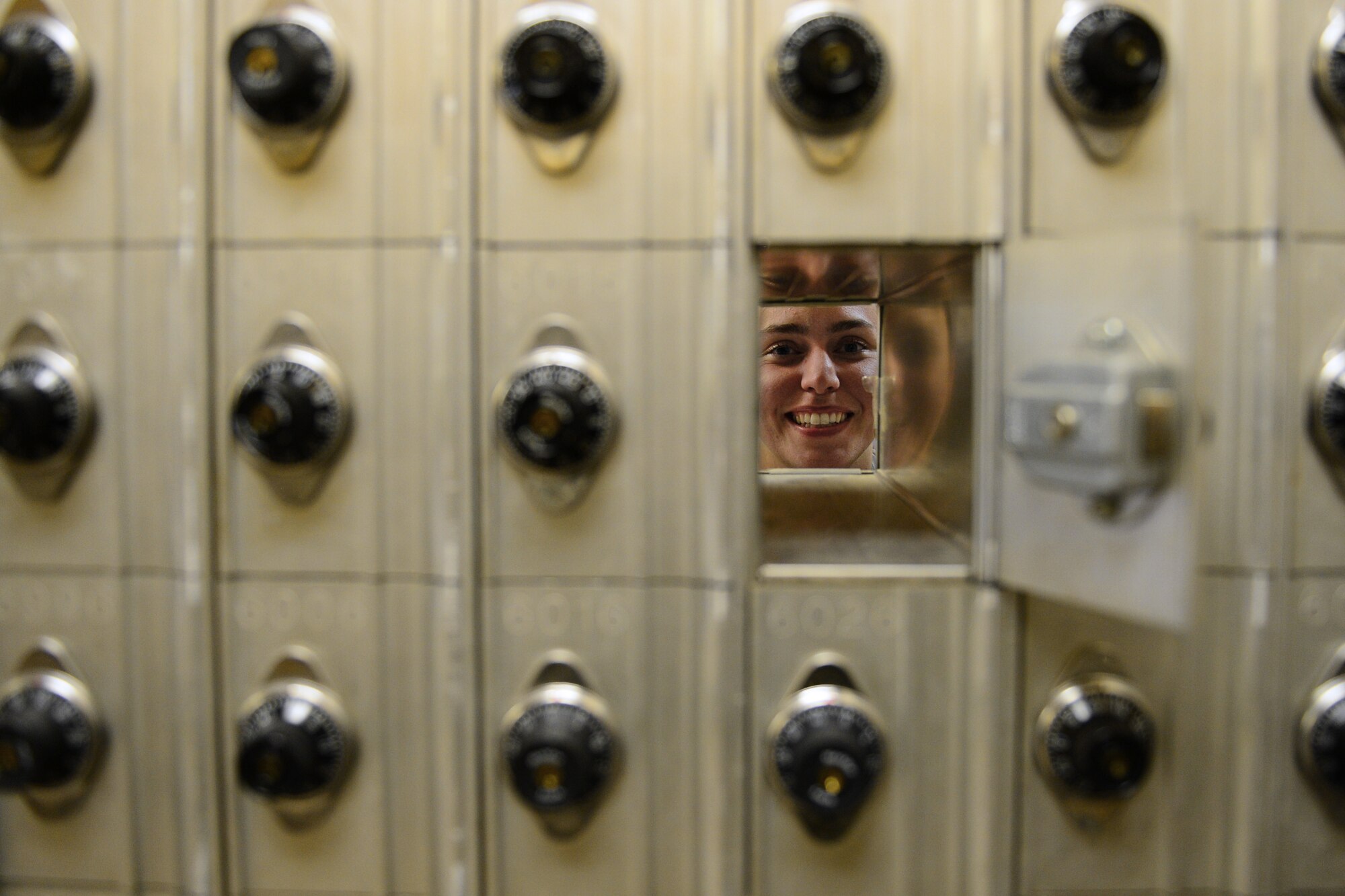 Senior Airman Megan Barker, 48th Communications Squadron military postal clerk, peers through mailboxes at Royal Air Force Lakenheath, England, June 5, 2015. Barker was nominated for a Liberty Spotlight because she embodies the core values of Service Before Self and Excellence In All We Do. (U.S. Air Force photo by Airman 1st Class Erin R. Babis/Released)