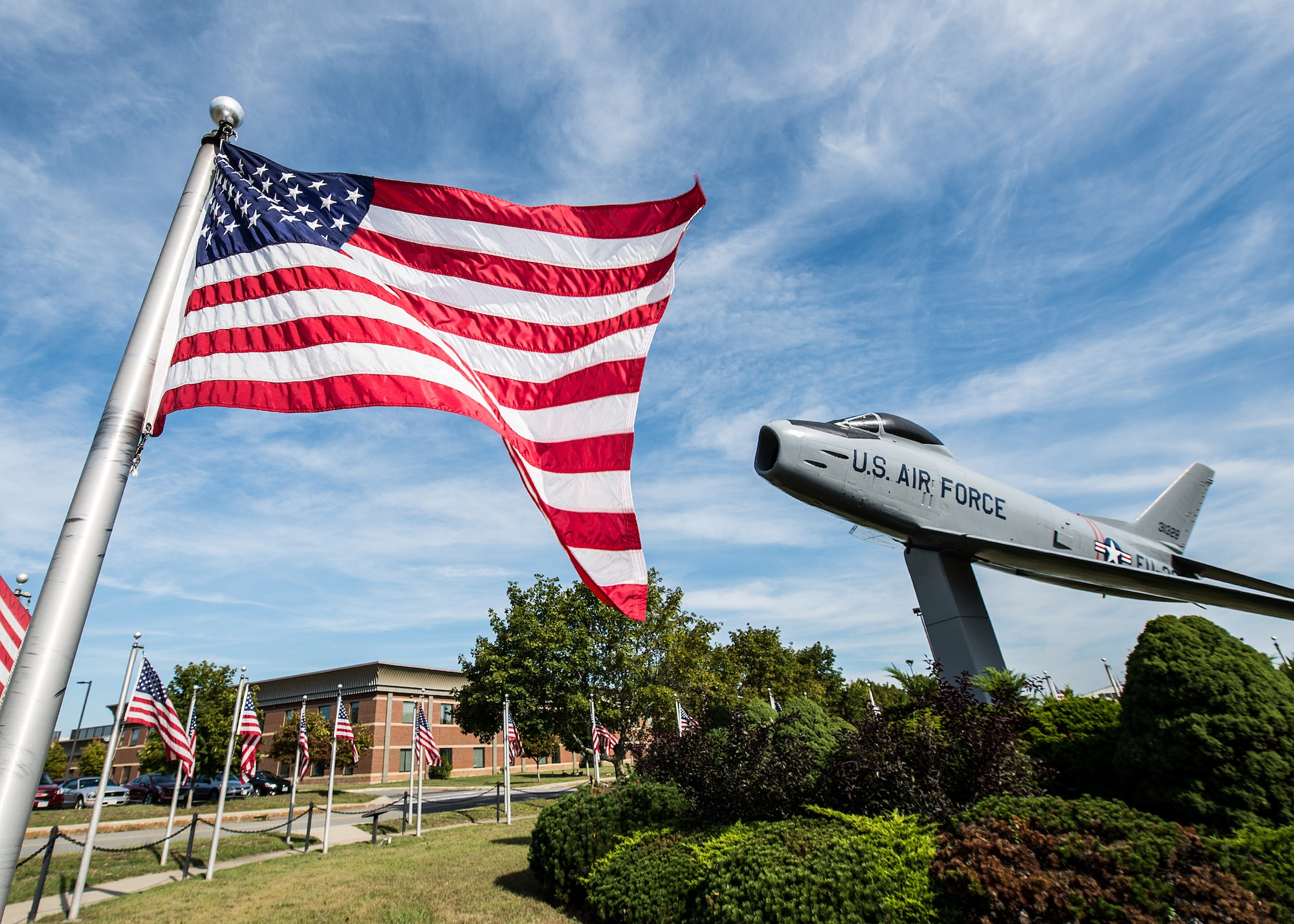 United States flags fly around the F-86 static display on base Sept. 9. Traditional guidelines call for displaying the flag in public only from sunrise to sunset. However, the flag may be displayed at all times if it’s illuminated during darkness. (U.S. Air Force photo by Mark Herlihy)