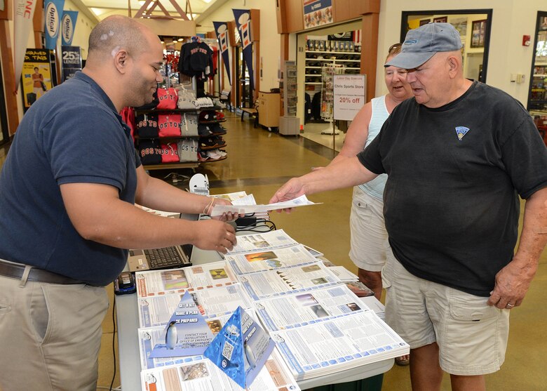 Michael Kaiser, 66th Civil Engineering Division emergency manager, hands Alex Exarhopoulos, a flyer on disaster preparedness at the Hanscom Exchange Sept. 9 while his wife, Dawn, looks on. Members of the Emergency Management Flight hosted an information booth to help educate the community on preparedness issues as part of National Preparedness Month. (U.S. Air Force photo by Jerry Saslav)