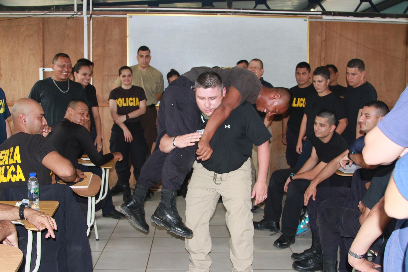 Sgt. 1st Class David Muniz, center, demonstrates a first aid buddy carry to 34 Costa Rican first responders from three agencies. Police officers, border patrol officers and Coast Guardsmen attended an exchange of information which included some classroom instruction with the majority of time spent conducting hands-on practical exercises. 