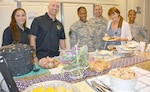 Sgt. Audie Murphy Club members (from left) Staff. Sgt. Amy Davis, president, Sgt. Audie Murphy Club; Sgt. 1st Class Justin Puls; Sgt. 1st Class Ebony Alexander; Sgt. 1st Class Rommel Fuentes; and Staff Sgt. Lekita Singleton, pose with a Fisher House resident who came by to pick up  some food provided by the club members for the residents. “We try to do this event semi-annually and we do it as a way to repay the families for their service and to appreciate what they are doing,” Davis said.