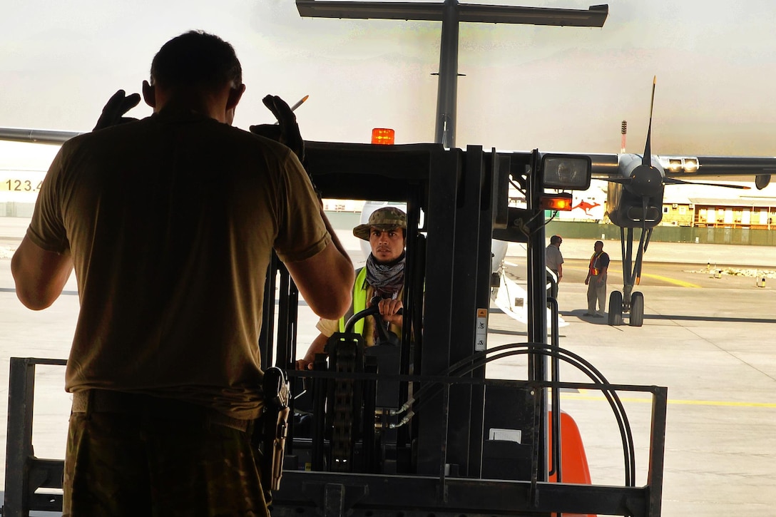 U.S. Air Force Staff Sgt. Casey Strauss, foreground, directs a cargo loader during a shipment pick-up at Hamid Karzai International Airport in Kabul, Afghanistan, Aug. 28, 2015. Strauss is a loadmaster assigned to the 774th Expeditionary Airlift Squadron. U.S. Air Force photo by Senior Airman Cierra Presentado