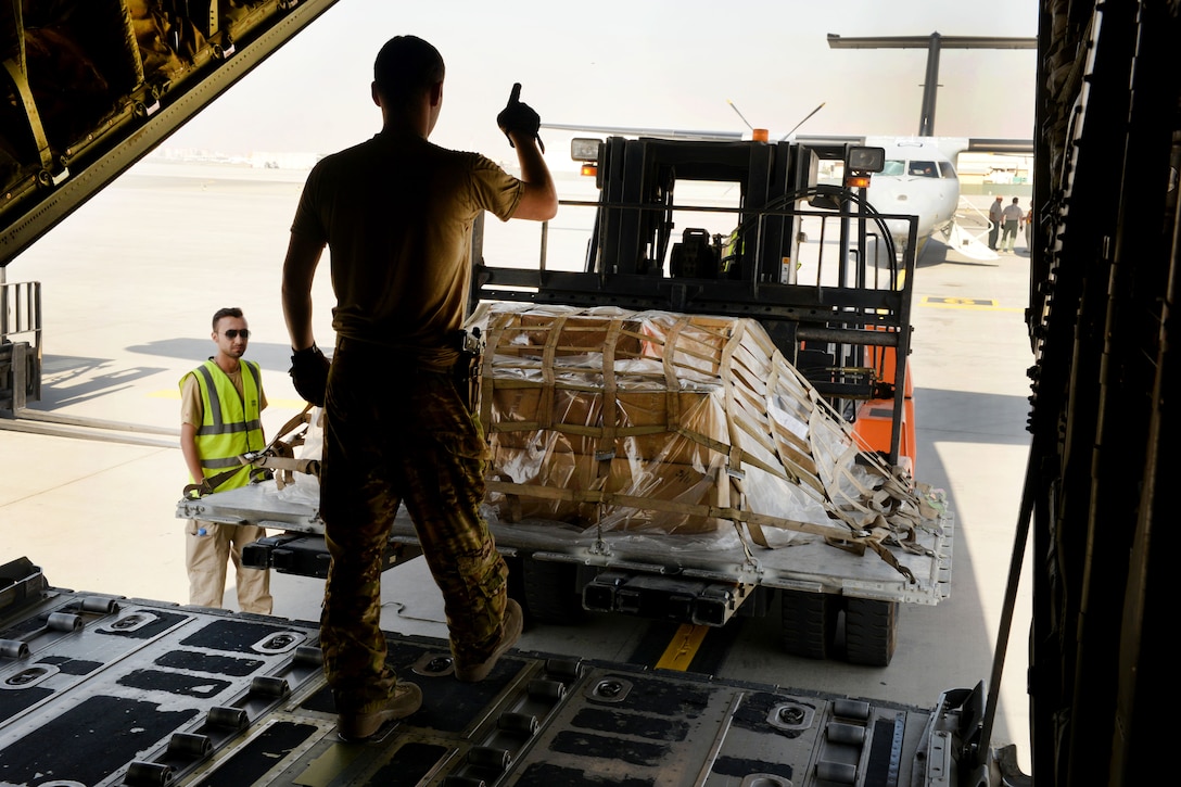 U.S. Air Force Staff Sgt. Casey Strauss, foreground, gives directions to a cargo loader during a shipment pick-up at Hamid Karzai International Airport in Kabul, Afghanistan, Aug. 28, 2015. Strauss is a loadmaster assigned to the 774th Expeditionary Airlift Squadron. U.S. Air Force photo by Senior Airman Cierra Presentado