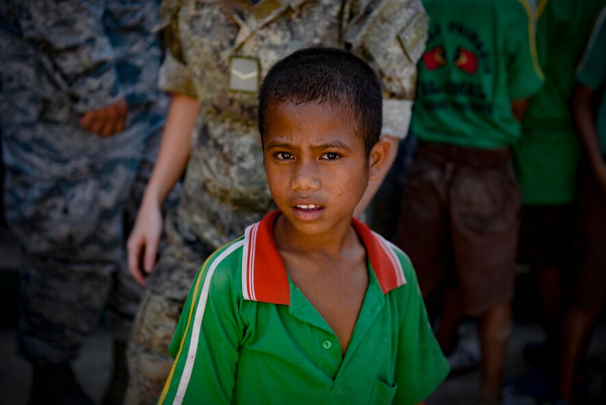 A student of the Al-Amal primary school watches a rice donation to the neighbouring orphanage by Pacific Angel 15-2 team members Sept. 8, 2015, in Baucau, Timor-Leste. Efforts undertaken during Pacific Angel help multilateral militaries in the Pacific improve and build relationships across a wide spectrum of civic operations, which bolsters each nation’s capacity to respond and support future humanitarian assistance and disaster relief operations. (U.S. Air Force photo/Staff Sgt. Alexander W. Riedel/Released)