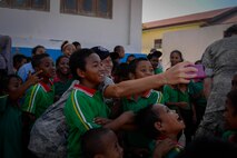 Maj. (Dr.) Kimberly Caldwell, 18th Medical Group family practice physician, takes a selfie with students of the Al-Amal primary school during a rice donation to the neighbouring orphanage Sept. 8, 2015, in Baucau, Timor-Leste. Efforts undertaken during Pacific Angel help multilateral militaries in the Pacific improve and build relationships across a wide spectrum of civic operations, which bolsters each nation’s capacity to respond and support future humanitarian assistance and disaster relief operations. (U.S. Air Force photo/Staff Sgt. Alexander W. Riedel/Released)