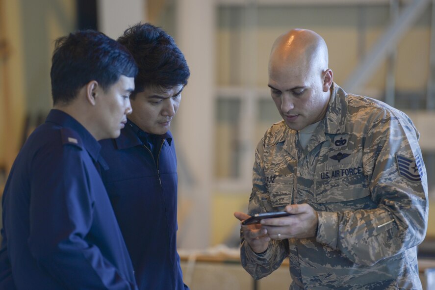 Tech. Sgt. Christian Ruiz, 374th Logistical Readiness Squadron combat mobility flight NCO in charge of operations, shows U.S. Air Force projects on his phone to members of the Philippine Air Force during the 2015 Pacific Agility Logistics and Safety Symposium at Yokota Air Base, Japan, Sept. 2, 2015. The symposium is a U.S. Pacific Command initiative aimed at increasing interoperability between regional partners. (U.S. Air Force photo by Staff Sgt. Cody H. Ramirez/Released)