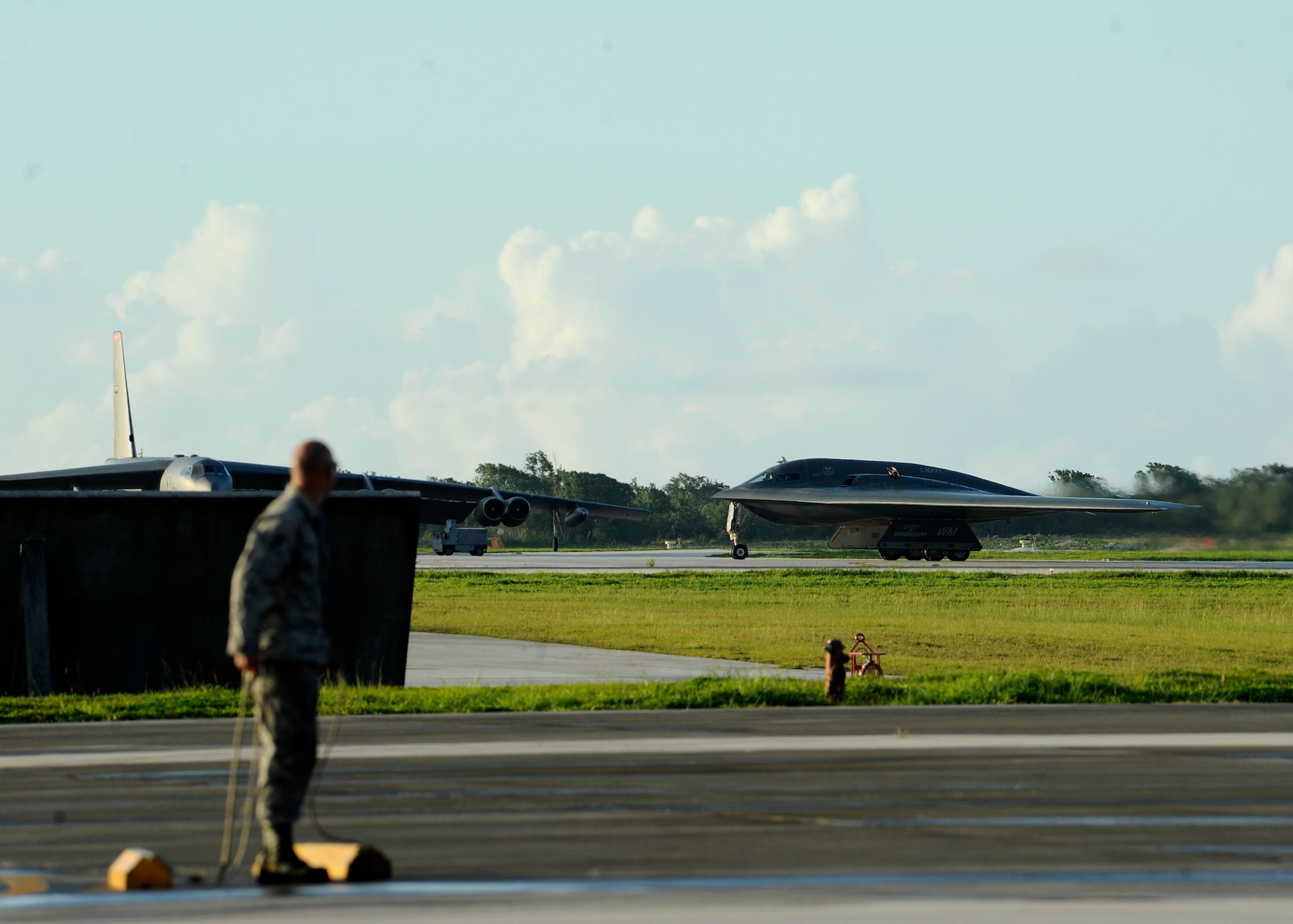 Senior Airman Trace Tusing, 509th Aircraft Maintenance Squadron crew chief, Whiteman Air Force Base, Mo., marshals a B-2 Spirit bomber on the flightline at Andersen Air Force Base, Guam, Aug. 26, 2015. Whiteman deployed approximately 225 Airmen and three B-2s here to conduct familiarization training in the Indo-Asia-Pacific region. (U.S. Air Force photo by Senior Airman Joseph A. Pagán Jr./Released)