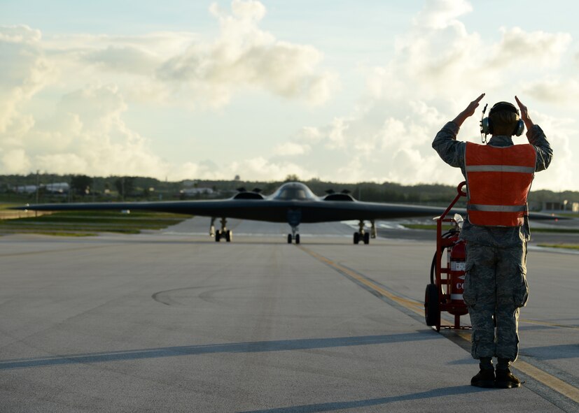 Senior Airman Trace Tusing, 509th Aircraft Maintenance Squadron crew chief, Whiteman Air Force Base, Mo., marshals a B-2 Spirit bomber on the flightline at Andersen Air Force Base, Guam, Aug. 26, 2015. Whiteman deployed approximately 225 Airmen and three B-2s here to conduct familiarization training in the Indo-Asia-Pacific region. (U.S. Air Force photo by Senior Airman Joseph A. Pagán Jr./Released)
