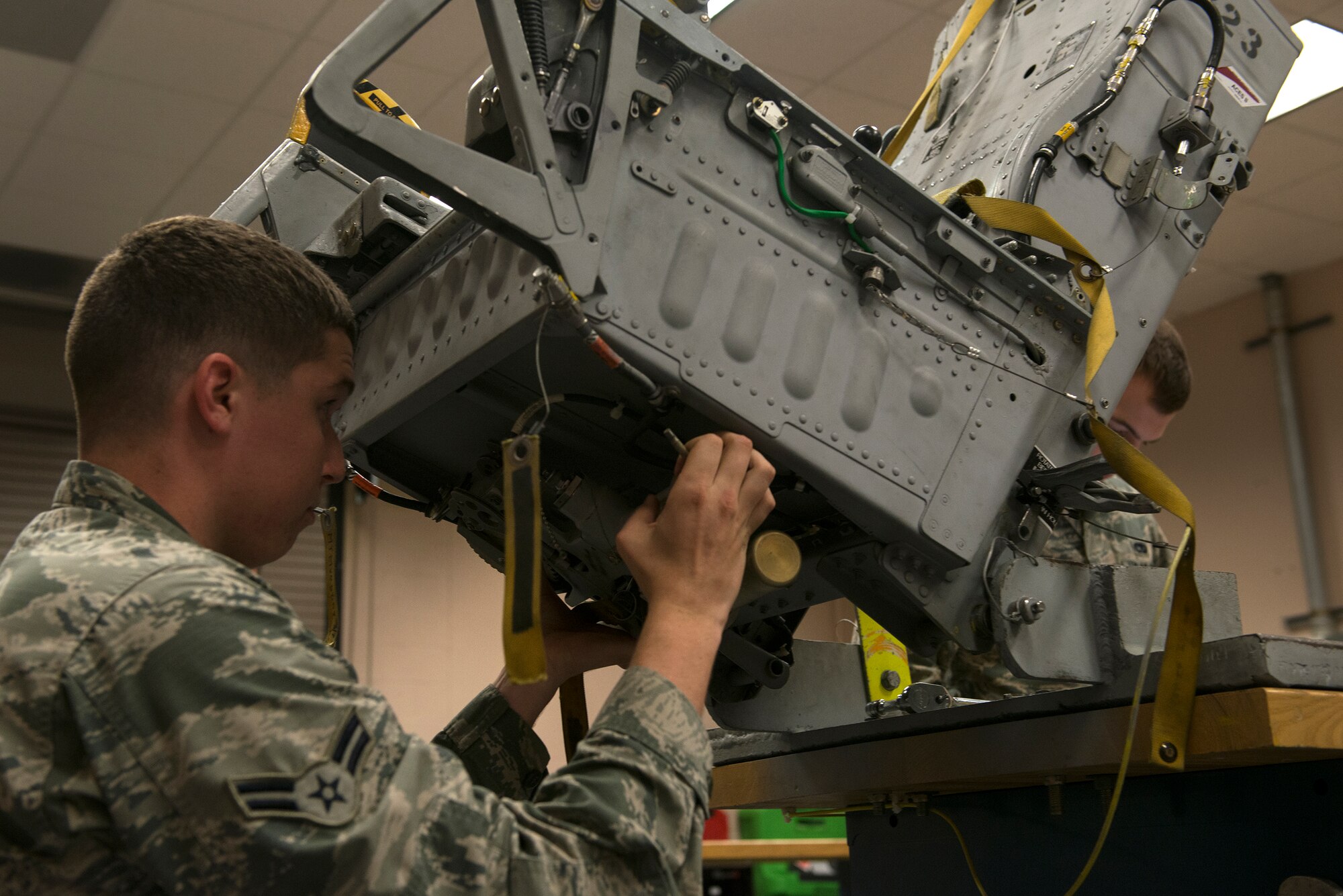 U.S. Air Force Airman 1st Class Caleb Luna, 23d Component Maintenance Squadron aircrew egress systems journeyman, reinstalls a seat pan on an ejection seat Sept. 2, 2015, at Moody Air Force Base, Ga. An A-10C Thunderbolt II seat contains 13 explosives in order to eject it out of the aircraft in case of an emergency. (U.S. Air Force photo by Airman 1st Class Kathleen D. Bryant/Released)

