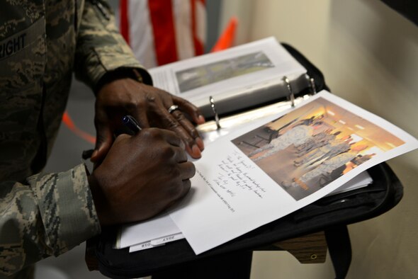 U.S. Air Force Chief Master Sgt. Kaleth Wright, Third Air Force and 17th Expeditionary Air Force command chief, signs a “Square D” Heritage display book Sept. 9, 2015, on RAF Mildenhall, England. Wright and U.S. Air Force Lt. Gen. Timothy Ray, Third Air Force and 17th Expeditionary Air Force commander, were asked to sign the heritage book to log the history of distinguished visitors that viewed the display. (U.S. Air Force photo by Staff Sgt. Micaiah Anthony/Released)