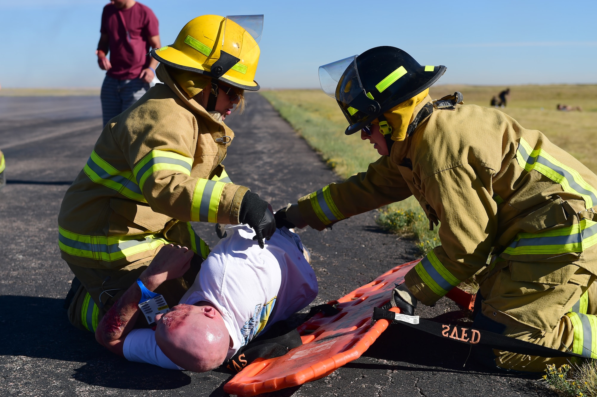 Bennett Fire Department first responders move a simulated casualty onto a stretcher Sept. 10, 2015, at Front Range Airport, Colo. A joint operation was conducted by Buckley Air Force Base and surrounding community emergency responders during an annual major accident response exercise. (U.S. Air Force photo by Airman 1st Class Luke W. Nowakowski/Released)