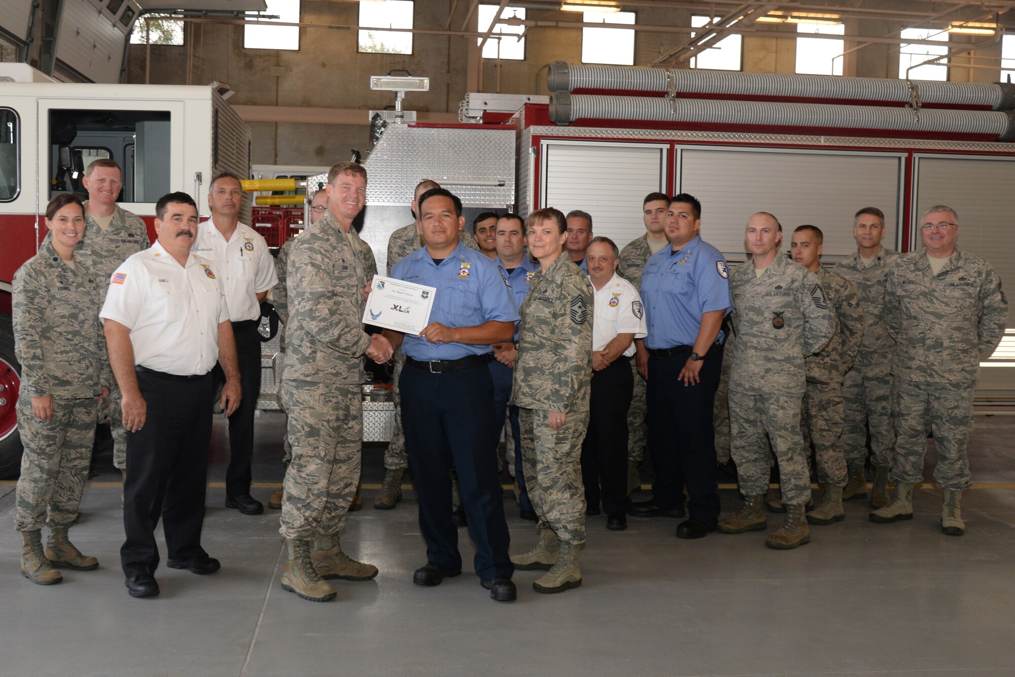 Miguel Chacon, center, 47th Civil Engineer Squadron lead firefighter, poses with Col. Thomas Shank, 47th Flying Training Wing commander, and Chief Master Sgt. Teresa Clapper, 47th FTW command chief, after accepting the “XLer of the Week” award, here, Sep. 10, 2015. The “XLer” is a weekly award chosen by wing leadership and is presented to those who consistently make outstanding contributions to their unit and Laughlin. (U.S. Air Force photo by Airman 1st Class Brandon May) (Released)