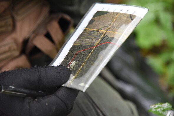 U.S. Air Force Capt. James Broncheau, 13th Fighter Squadron chief of plans and mobility, examines a map of his surroundings during a combat survival training exercise at Draughon Range, Japan, Sept. 9, 2015. During the CST, Broncheau simulated egressing into enemy territory, needing to escape alive in a certain amount of time. The designated area for CSTs in Draughon Range covers approximately one square-kilometer of terrain to navigate. (U.S. Air Force photo by Senior Airman Patrick S. Ciccarone/Released)