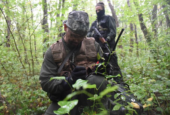 U.S. Air Force Capt. James Broncheau, 13th Fighter Squadron chief of plans and mobility, communicates over radio his coordinates during a combat survival training exercise at Draughon Range, Japan, Sept. 9, 2015. During the exercise, Broncheau was captured by hostile combatants and brought back to a makeshift village for interrogation. When a pilot is captured during these exercises, they are required to report their location and status to a waiting survive, evade, resist and escape specialist, providing them guidance on how to stay alive . (U.S. Air Force photo by Senior Airman Patrick S. Ciccarone/Released) 
