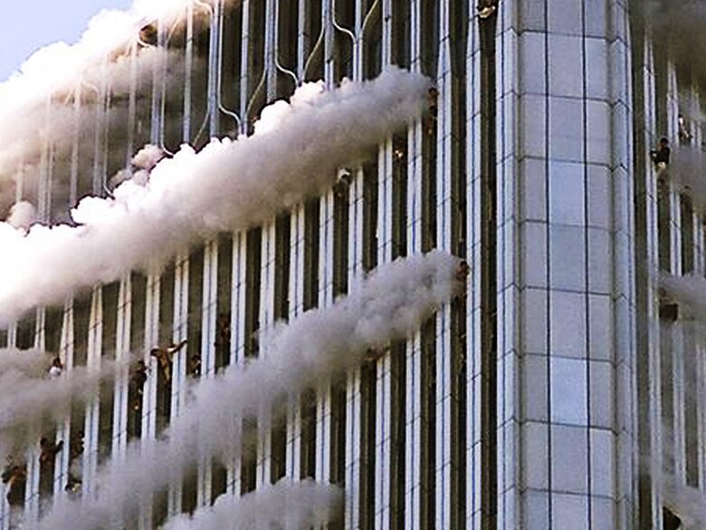 Driven out of the building by fires and scorching temperatures, people near the top of the World Trade Center's North Tower hang from windows as high as 1,300-feet above the streets of New York City, Sept. 11, 2001. Hijackers crashed American Airlines Flight 11 into floors 93 through 99 of the North Tower. (Getty Images photo by Jose Jimenez/Released)