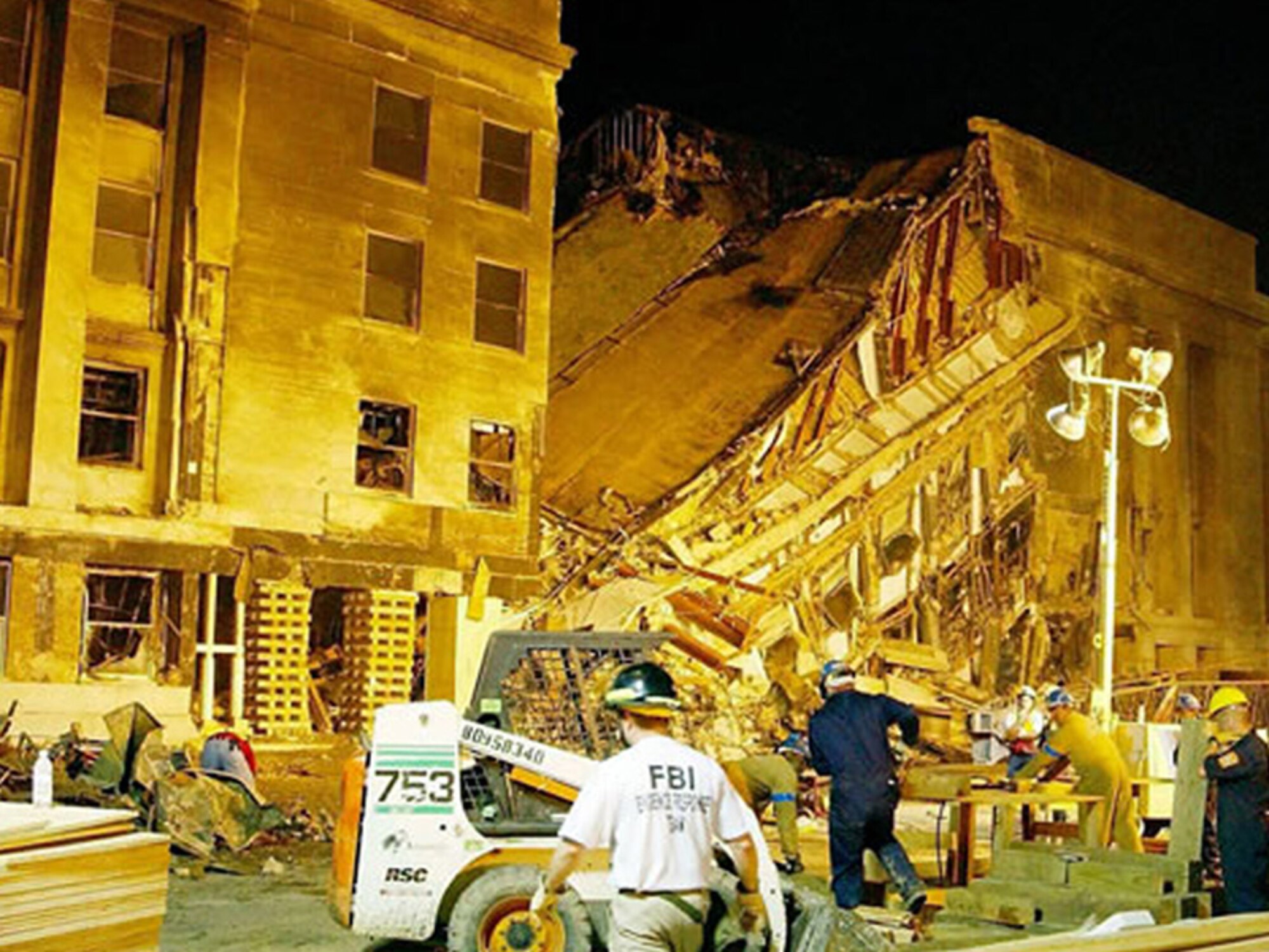 Emergency responders and firefighters work through the night, searching for survivors at the Pentagon, Sept. 11, 2001. The damage was caused when an aircraft, hijacked by al-Qaida terrorists, was deliberately crashed into the side of the building. (Corbis photo by Bill Vaughan/Released)