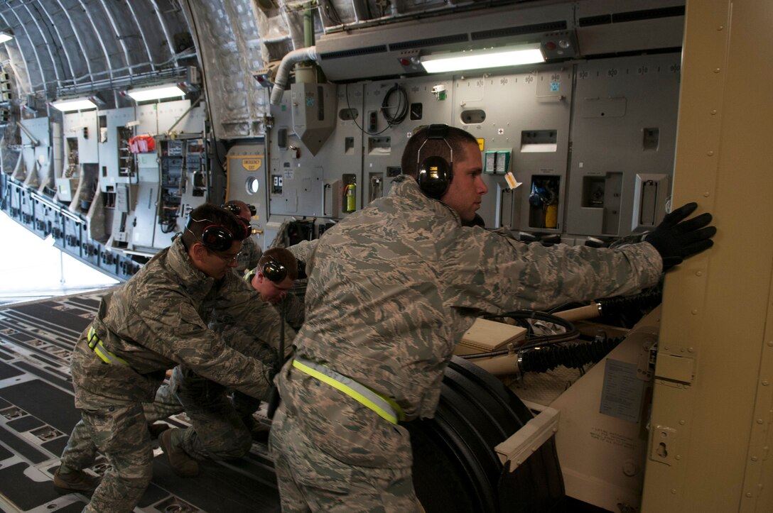 U.S. Air Force Capt. Zachary Clark, commander of the Deployment and Distribution Flight under the Logistics Readiness Squadron, helps a crew load cargo onto a C-17. The LRS team is responsible for ensuring all cargo is properly weighed, loaded and secured on the aircraft. (U.S. Air National Guard photo by Airman 1st Class Dana Alyce-Schwarz)