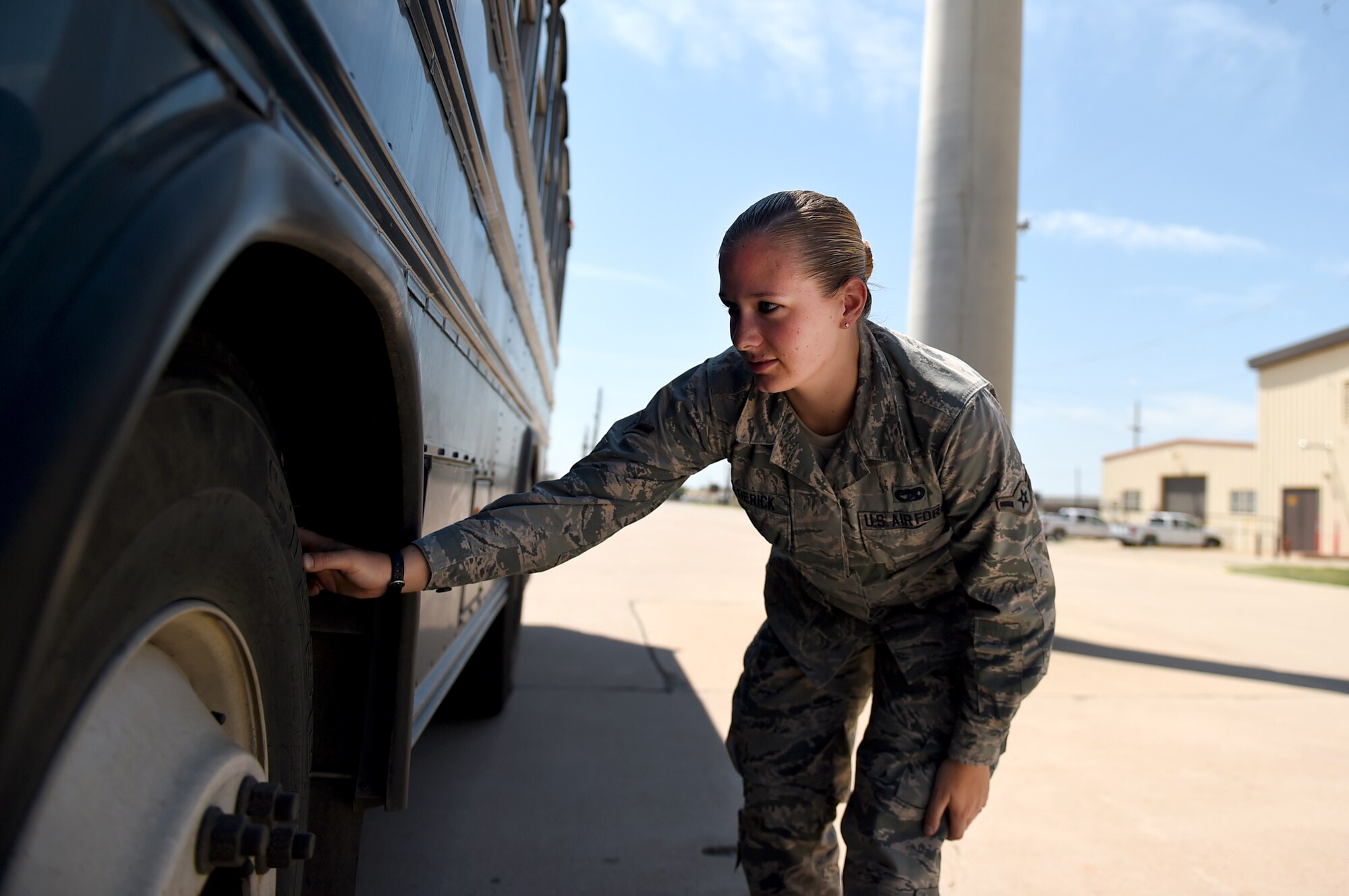 ALTUS AIR FORCE BASE, Okla. – U.S. Air Force Airman Becca Fredericks, 97th Logistics Readiness Squadron vehicle operations operatior, checks for foregin objects of destruction around a bus before driving on the flightline, Sept. 3, 2015. FOD walks must be done whenever a vehicle goes on the flightline to prevent objects like rocks and nails from being sucked in to the aircraft engines. (U.S. Air Force photo by Airman 1st Class Kirby Turbak/Released)