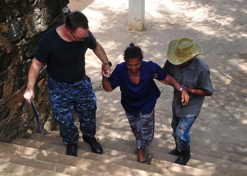 TRUJILLO, Honduras – Angela Brauman climbs stairs with the help of her son, Efrain, and a Sailor from the U.S.N.S. Comfort prior to receiving an eye exam as part of Continuing Promise 2015, in Trujillo, Honduras, Aug. 28, 2015. Angela was one of 25 patients whom the Honduran Government identified for eye treatment, and whom Joint Task Force-Bravo transported to Trujillo for care. (U.S. Air Force photo by Capt. Christopher Love)