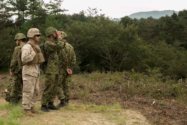Japanese Ground Self-Defense Force Col. Tadisha Tanida, middle right, and U.S. Marine Lt. Col. Eric Reid look at targets while Marines fire the shoulder-launched multipurpose assault weapon during Forest Light 16-1 at Camp Imazu, Takashima, Japan, Sept. 7, 2015. The JGSDF and U.S. Marines took turns sharing knowledge about different anti-tank missile systems. After giving specifications of their respective weapon systems, the two forces used practice rounds to demonstrate how well the weapon systems work. Forest Light will take place Sept. 7-18 with approximately 240 Marines working next to 350 JGSDF members. The exercise will consist of mortar live fire, establishing forward arming and refueling points training, helicopter borne skills and combined arms procedures. Tanida is the commanding officer of the 50th infantry regiment, 14th Brigade, JGSDF. Reid is the commanding officer of 1st Battalion, 2nd Marine Regiment currently assigned to 4th Marine Regiment, 3rd Marine Division, III Marine Expeditionary Force.