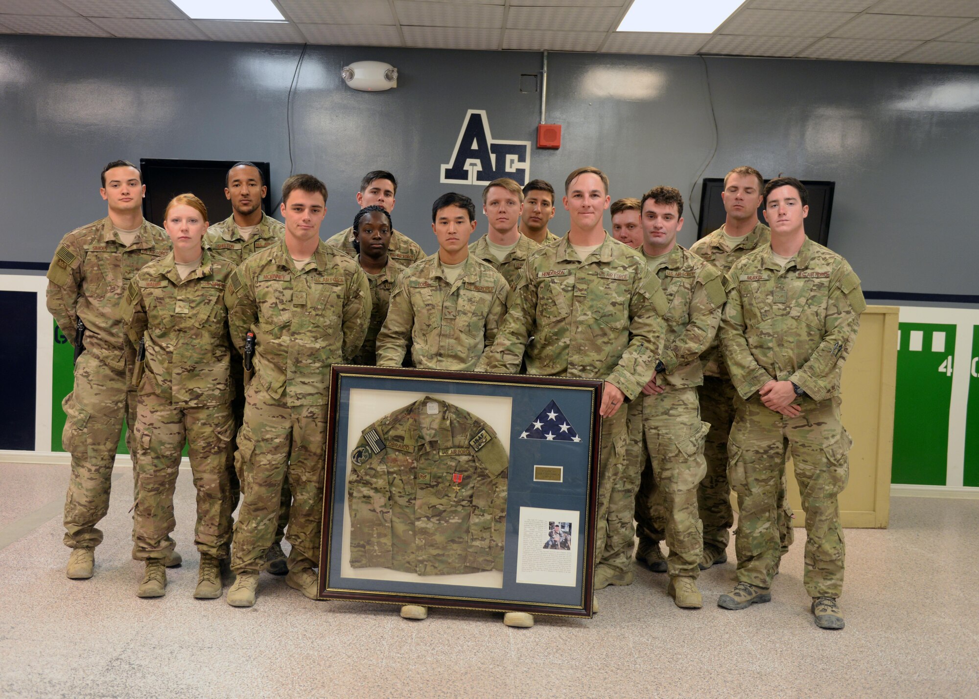 Members of the Task Force Crimson expeditionary detachment 2405, pose for a photo with a shadowbox dedicated to fallen hero Staff Sgt. Todd Lobraico after a dedication remembrance ceremony Sep. 5, 2015, at Bagram Airfield, Afghanistan. Members of BAF gathered to remember the sacrifice made by Lobraico when he lost his life during a fire fight against enemy forces while deployed here in 2013. (U.S. Air Force photo by Senior Airman Cierra Presentado/Released)  