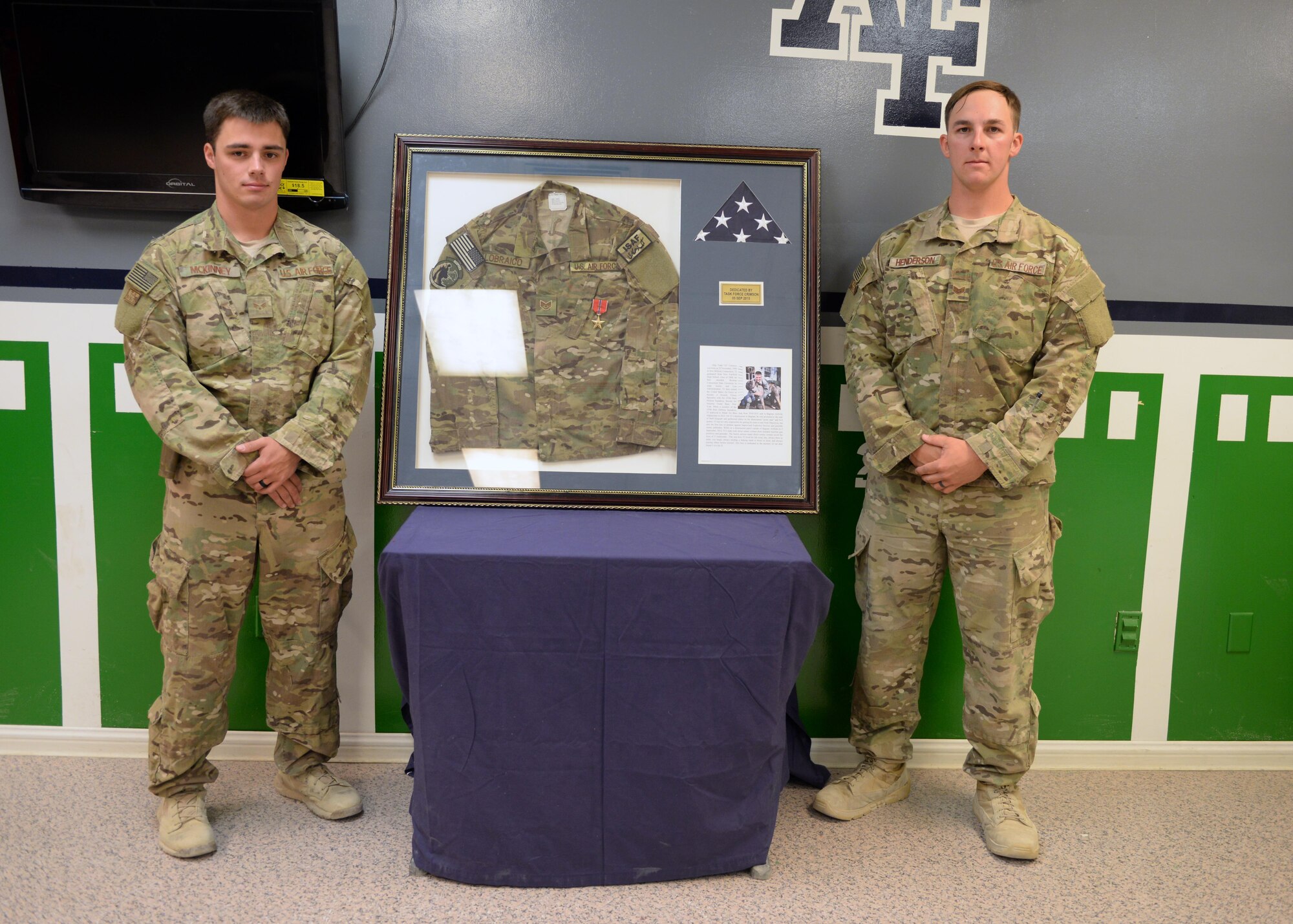 U.S Air Force Senior Airman  James McKinney, left, and Staff Sgt. Kyle Henderson, Task Force Crimson expeditionary detachment 2405 team members, pose for a photo next to a shadowbox dedicated to fallen hero Staff Sgt. Todd Lobraico during a dedication remembrance ceremony Sept. 5, 2015, at Bagram Airfield, Afghanistan. Members of BAF gathered to remember the sacrifice made by Lobraico when he lost his life during a fire fight against enemy forces while deployed here in 2013. (U.S. Air Force photo by Senior Airman Cierra Presentado/Released)  