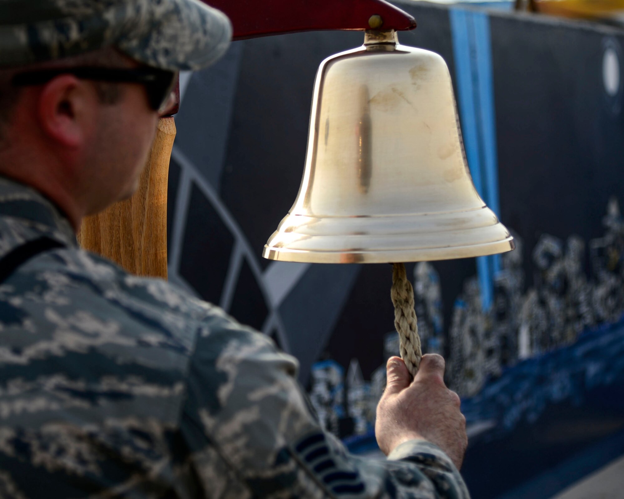 U.S. Air Force Tech. Sgt. Ed Kelly, 386th Expeditionary Civil Engineer Squadron assistant fire chief,  rings a bell while names of victims are read during a 9/11 tribute ceremony at an undisclosed location in Southwest Asia, Sept. 11, 2015. Kelly is an Air National Guardsman out of the 106th Civil Engineer Squadron currently supporting Operation Inherent Resolve, but is also a civilian firefighter and the third generation of his family to serve on the New York City Fire Department. (U.S. Air Force photo by Senior Airman Racheal E. Watson) 