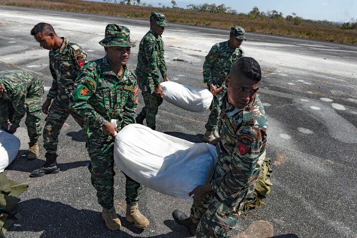 Soldiers with the  Falintil Forças de Defesa de Timor-Leste carry bags of rice that were just airdropped by a U.S. Air Force C-130 Hercules over Baucau airfield, Sept. 8, 2015, in Baucau, Timor-Leste. The packages were airdropped by a North Carolina Air National Guard C-130 crew during Operation Pacific Angel 15-2. Efforts undertaken during Pacific Angel help multilateral militaries in the Pacific improve and build relationships across a wide spectrum of civic operations, which bolsters each nation’s capacity to respond and support future humanitarian assistance and disaster relief operations. 