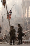 Two members of the National Guard stand beneath one of hundreds of American flags that have been hoisted or worn by rescue workers at the site of the collapsed World Trade Center in New York on Sept, 19, 2001.