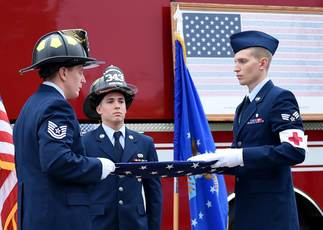 Members of the 97th Civil Engineer Squadron fire department and 97th Medical Group fold a flag during the 9/11 remembrance ceremony outside the base fire station, Sept. 11, 2015. Each fold of the flag represented a group of people who were strongly affected from the events of Sept. 11, 2001. (U.S. Air Force photo/Airman 1st Class Kirby Turbak)