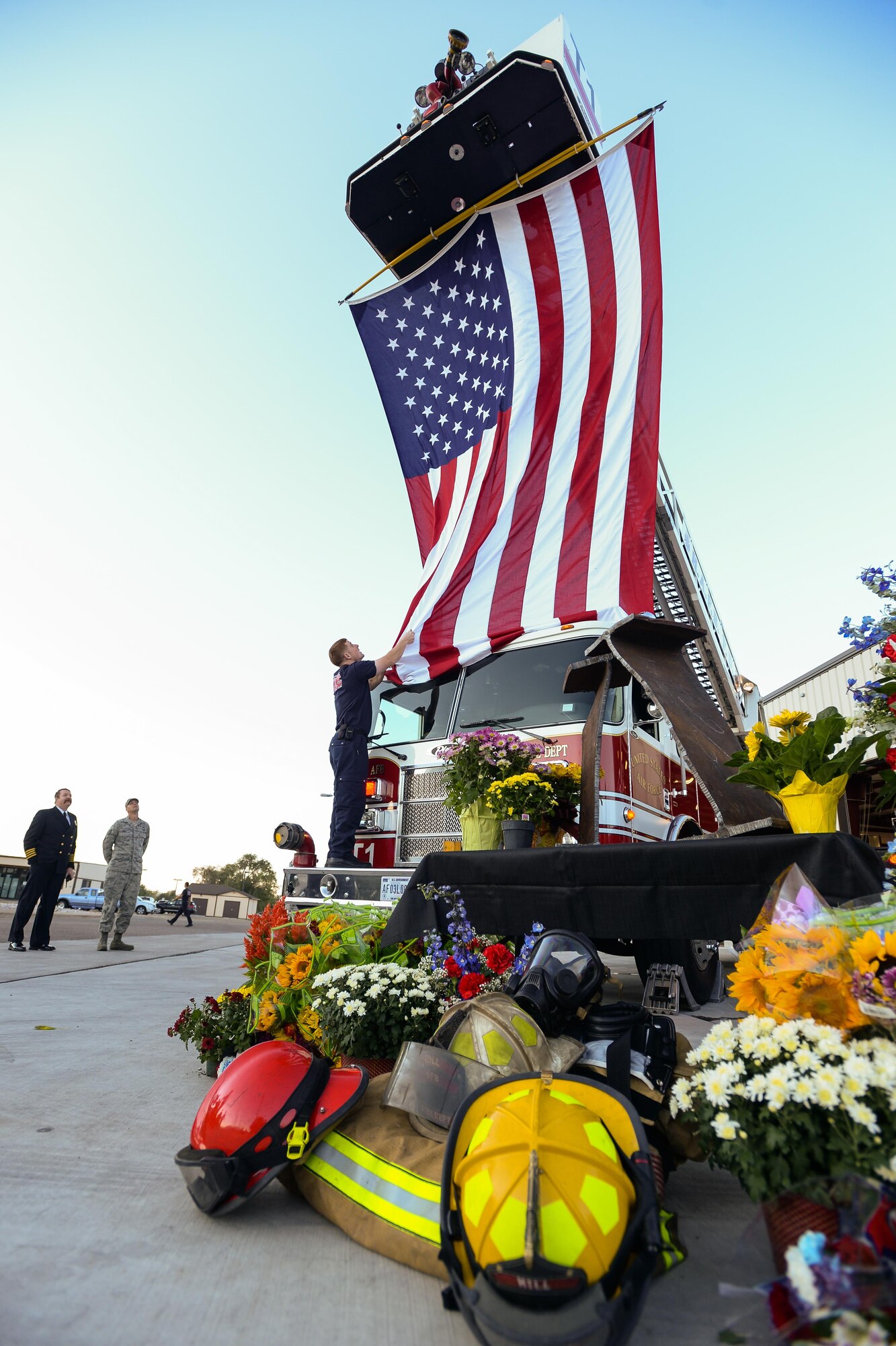 A firefighter arranges the bottom of an 18-foot long flag that was used for a 9/11 remembrance display in front of Fire House No. 1 at Hill Air Force Base, Utah, Sept. 11, 2015. The display included two iron girders, one from each of the World Trade Center Buildings, firefighter gear and flowers donated by local businesses. (U.S. Air Force photo/R. Nial Bradshaw)