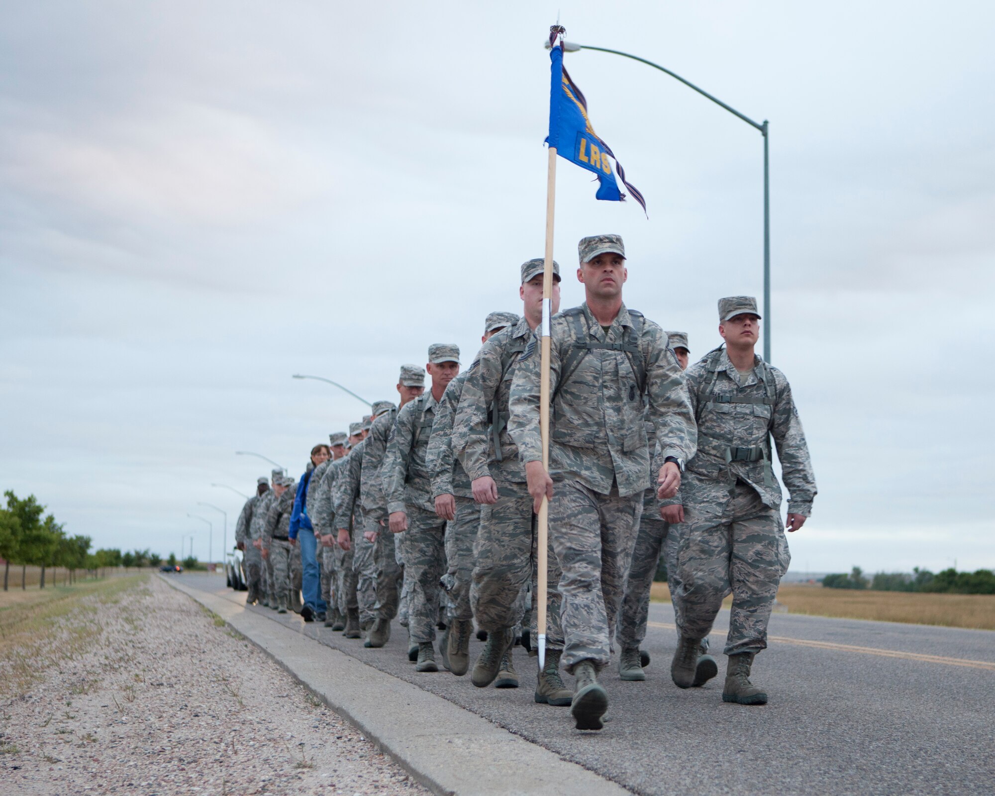 Airmen from 90th Logistics Readiness Squadron march down a base roadway while carrying rucksacks to commemorate the terrorist attacks against the U.S. in 2001, at F.E. Warren Air Force Base, Wyo. Sept. 11, 2015. This marks the fourth year the 90th LRS has made the march in memory of the lives lost that day. (U.S. Air Force photo/Lan Kim)