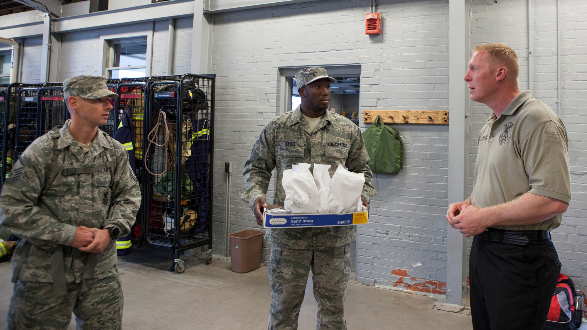 Master Sgt. Robert Wilson, 90th Logistics Readiness Squadron acting 1st sergeant and Senior Airman Joseph Bates, 90th LRS, present breakfast to Joshua Sarters, 90th Civil Engineer Squadron fire department assistant chief of training, on F.E. Warren Air Force Base, Wyo.,  Sept. 11, 2015. Airmen from 90th LRS ruck marched to commemorate the Sept. 11 attacks and honor F.E. Warren's first responders by visiting the fire station and the front gate. (U.S. Air Force photo by Lan Kim)