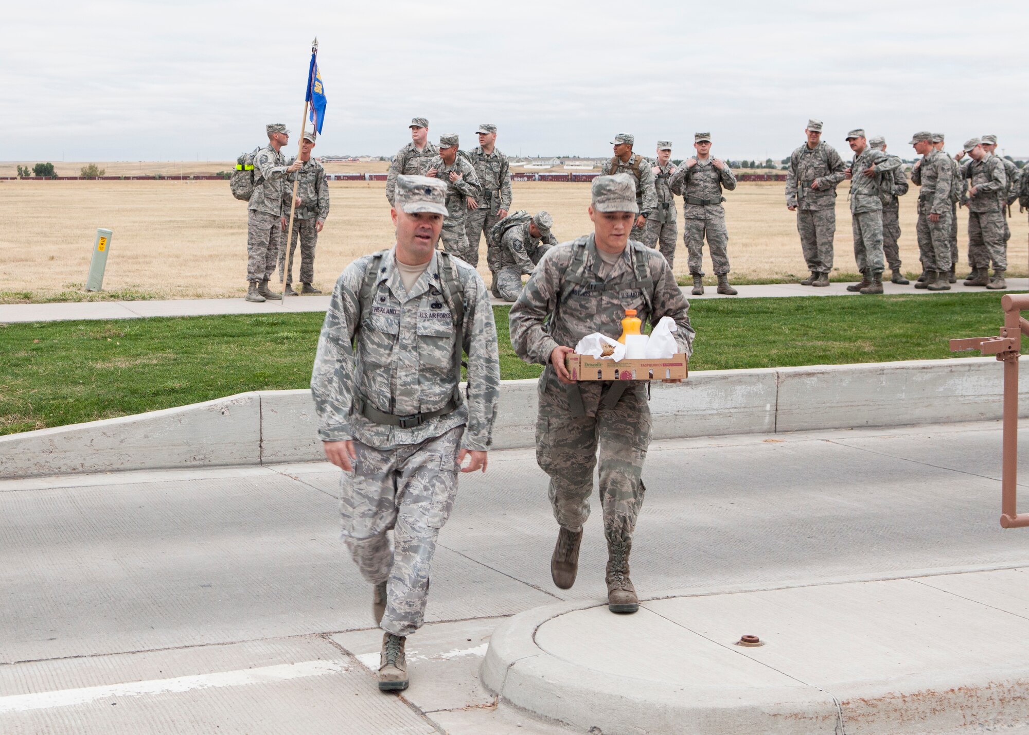 Lt. Col. Ross Sutherland, 90th Logistics Readiness Squadron commander and Airman 1st Class Steven Hastings, 90th LRS, arrive at the front gate of F.E. Warren Air Force Base, Wyo., to present breakfast to entry controllers, Sept. 11, 2015. Airmen from 90th LRS ruck marched to commemorate the Sept. 11 attacks and honor F.E. Warren's first responders by visiting the fire station and the front gate to thank them for their service. (U.S. Air Force photo by Lan Kim)