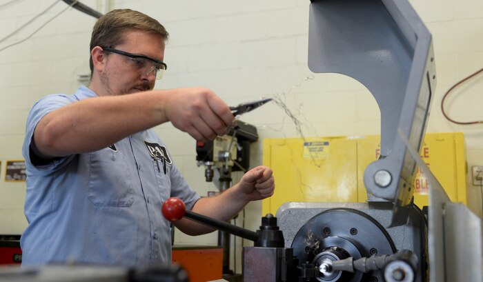 Nathan Reeder, 57th Maintanence Group aerospace machinist, plies excess metal out of a fabrication machine at the Aircraft Metals Technology shop on Nellis Air Force Base, Nev., Sept. 3, 2015. The mission of the metals shop is to design, weld and fabricate machine precision tools, components and assemblies for aerospace weapon systems and other support equipment. (U.S. Air Force photo by Airman 1st Class Mikaley Kline)