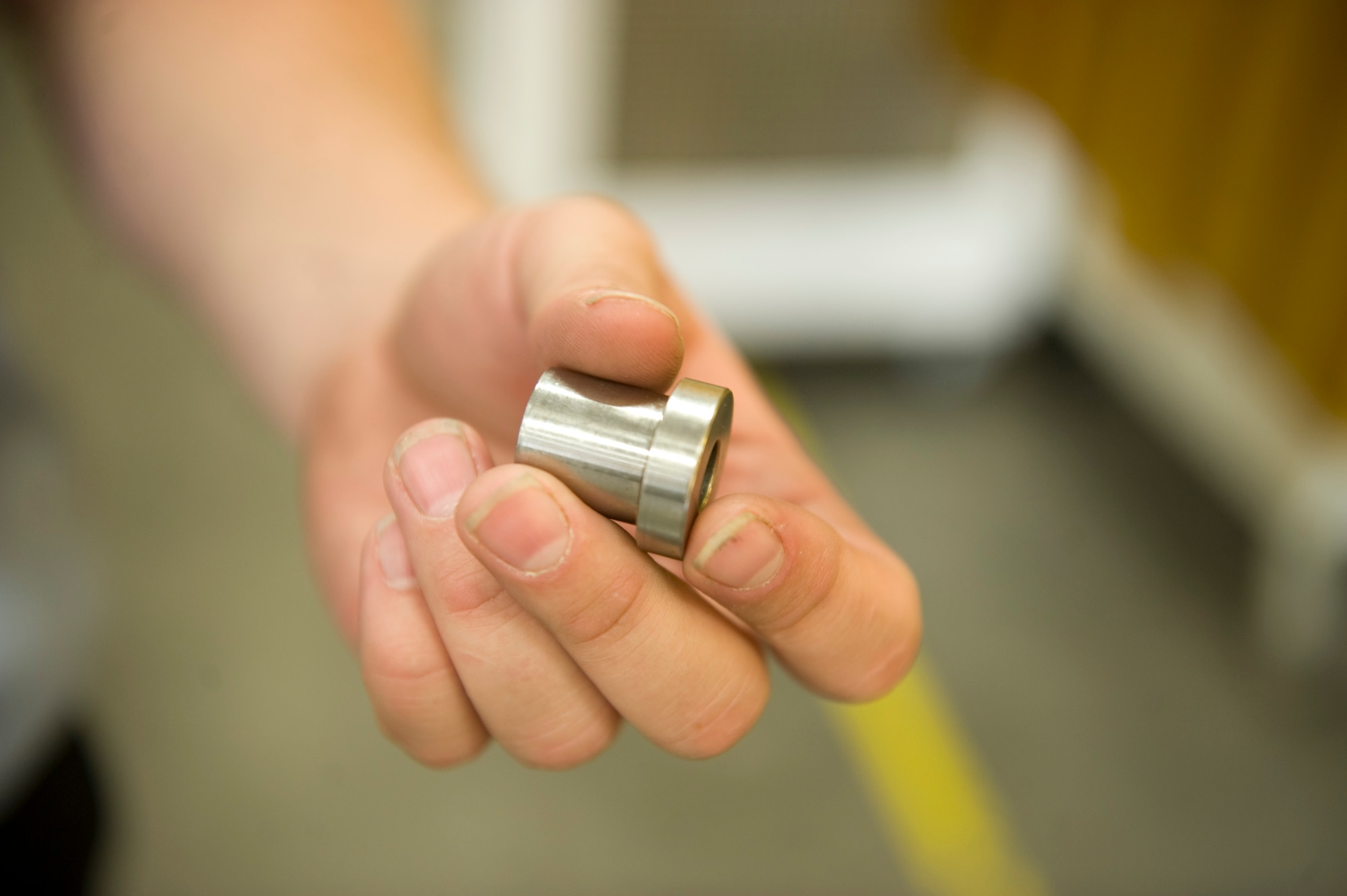 Nathan Reeder, 57th Maintanence Group aerospace machinist, holds up a bushing at the Aircraft Metals Technology shop on Nellis Air Force Base, Nev., Sept. 3, 2015. Metals technology workers are responsible for designing, welding, repairing and fabricating aircraft and aircraft ground equipment parts. (U.S. Air Force photo by Airman 1st Class Rachel Loftis)