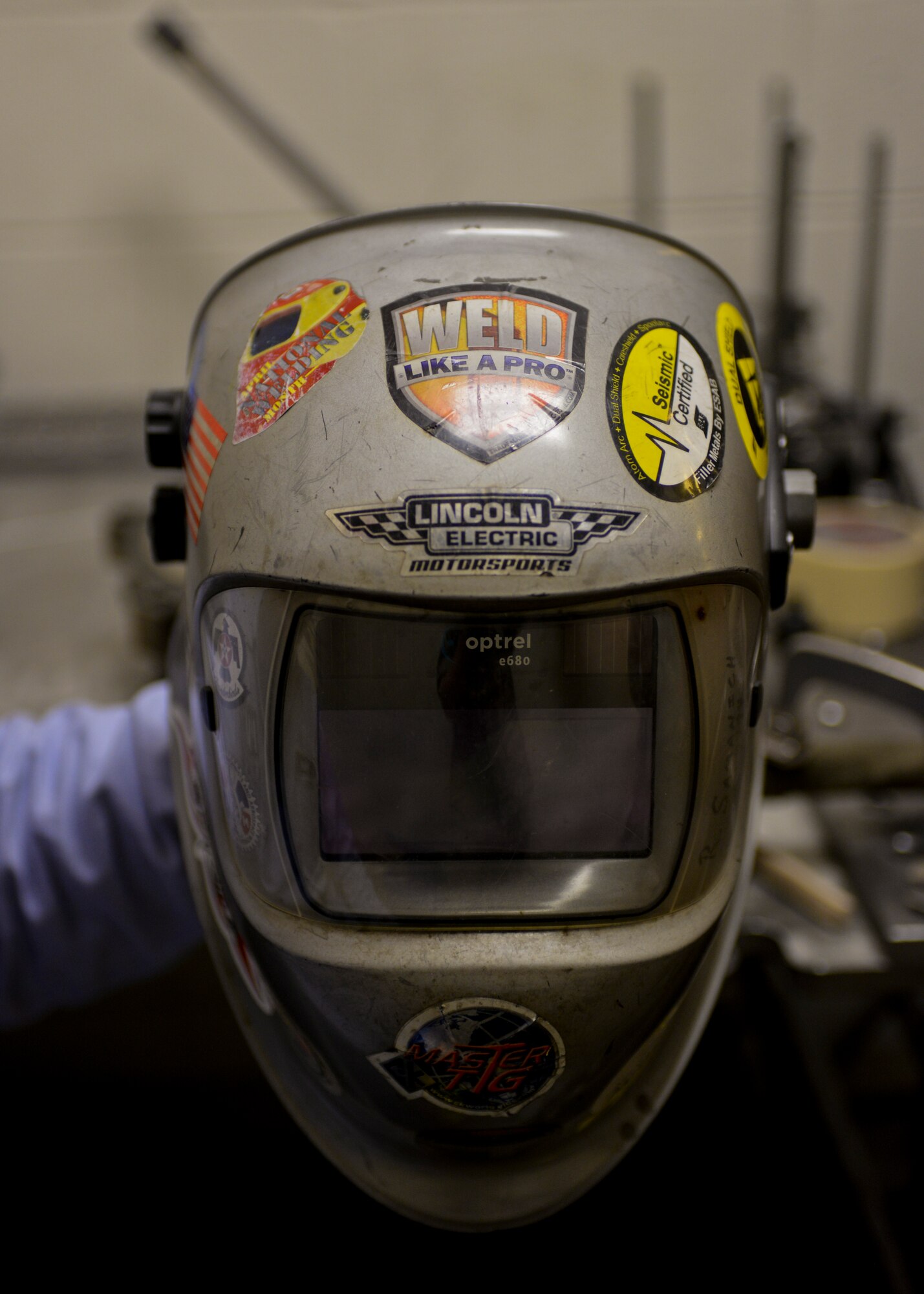 Rich Samanich, 57th Maintanence Group aircraft metals technology lead, holds up his welding helmet at the Aircratft Metals Tecnology shop on Nellis Air Force Base, Nev., Sept. 3, 2015. Metals technology workers have to don protective gear to avoid possible injury. (U.S. Air Force photo by Airman 1st Class Mikaley Kline)
