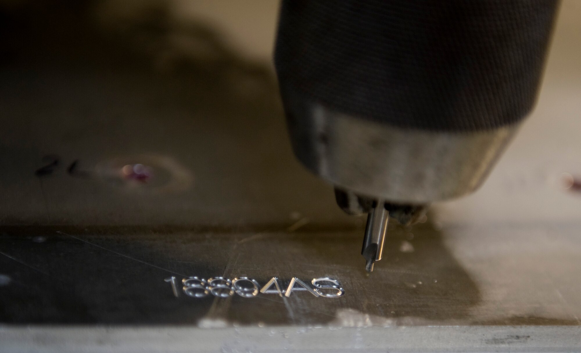 A Vertical Milling Center engraves a number into a piece of metal at the Aircraft Metals Technology shop on Nellis Air Force Base, Nev., Sept. 3, 2015. Numbers are engraved to identify the metal parts and who they are going to based on the receiving shops needs. (U.S. Air Force photo by Airman 1st Class Rachel Loftis)