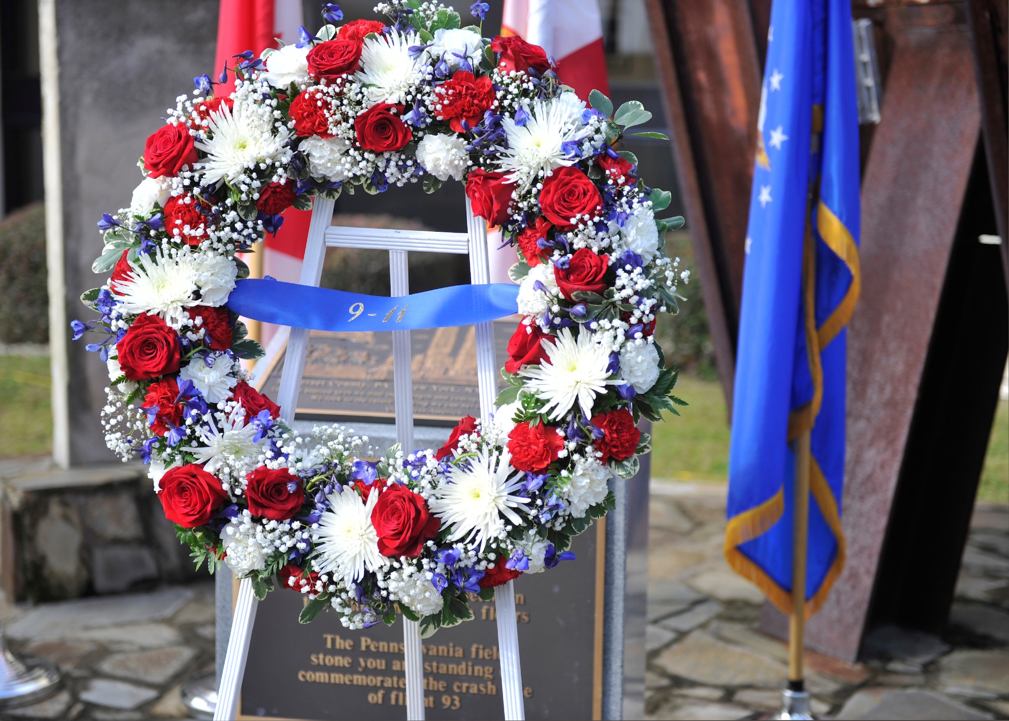 The wreath of red white and blue flowers stands in front of the charred granite stone from the Pentagon at the 601st Air Operations Center’s 9/11 Memorial. Placement of the wreath was part of a remembrance ceremony there Sept. 11. (Air Force Photo Released/Airman 1st Class Sergio Gamboa)