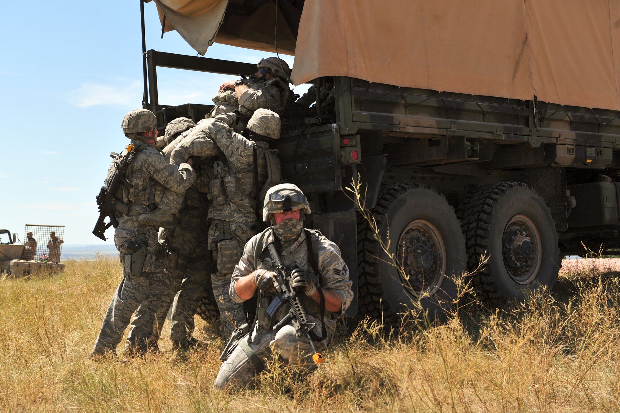 Air Force Reservists lift simulated wounded onto a military truck while an Airman provides rear cover during an ambush Aug. 13, 2015, at Camp Guernsey, Wyo. The 310th, 710th and 919th Security Forces Squadrons held a two-week field training exercise while living in field conditions.
(U.S. Air Force photos/Tech. Sgt. Nicholas B. Ontiveros)