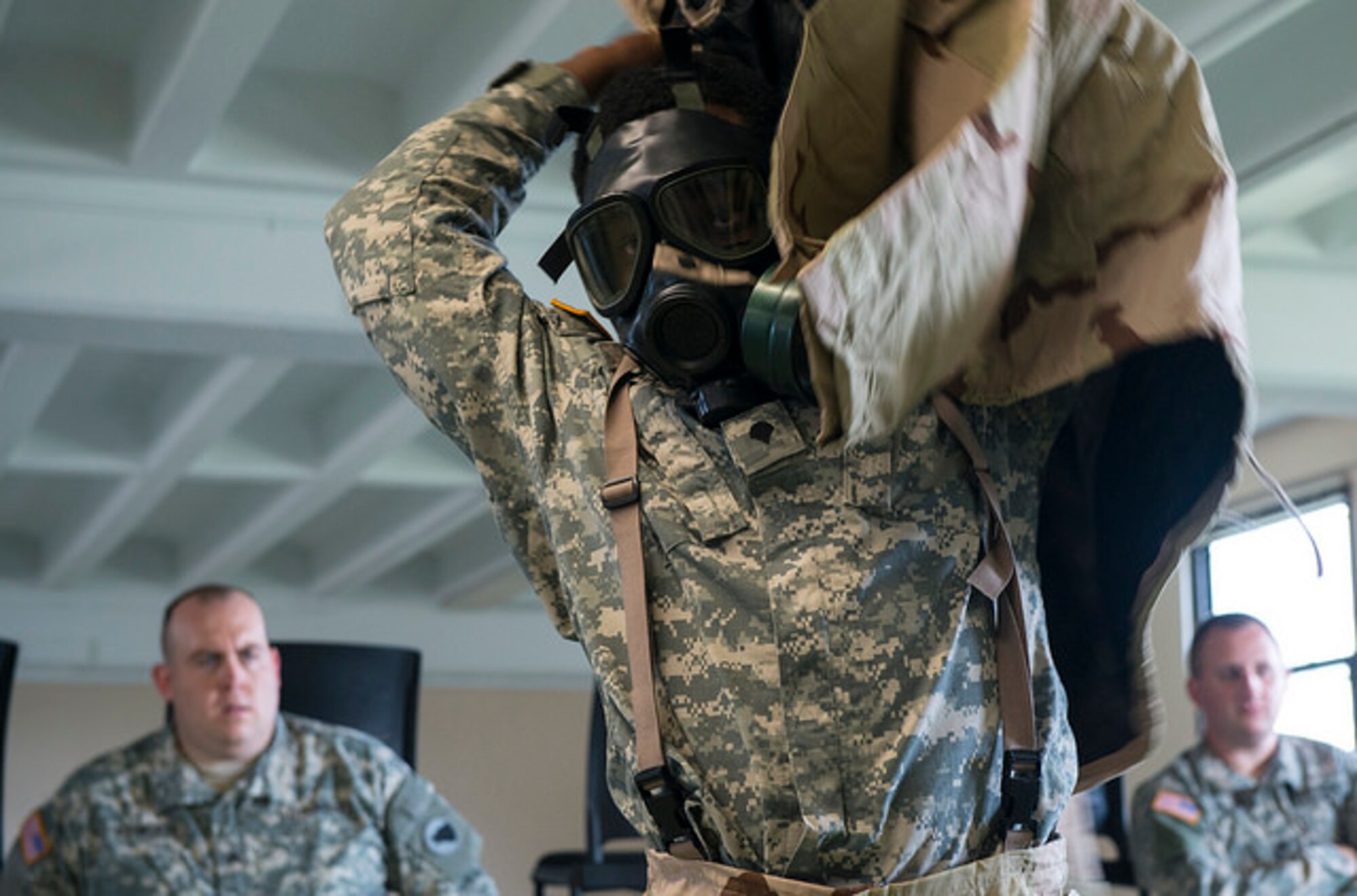Spc. Derrick Bonney, 1st Battalion, 391st Regiment, puts on a mission oriented protective posture jacket during a German Armed Forces Qualification Badge assessment on Joint Base McGuire-Dix-Lakehurst, N.J. Sept. 1, 2015. Sixteen Soldiers attempted to earn the badge and 10 passed the course. (U.S. Air Force photo by Airman 1st Class Joshua King)
