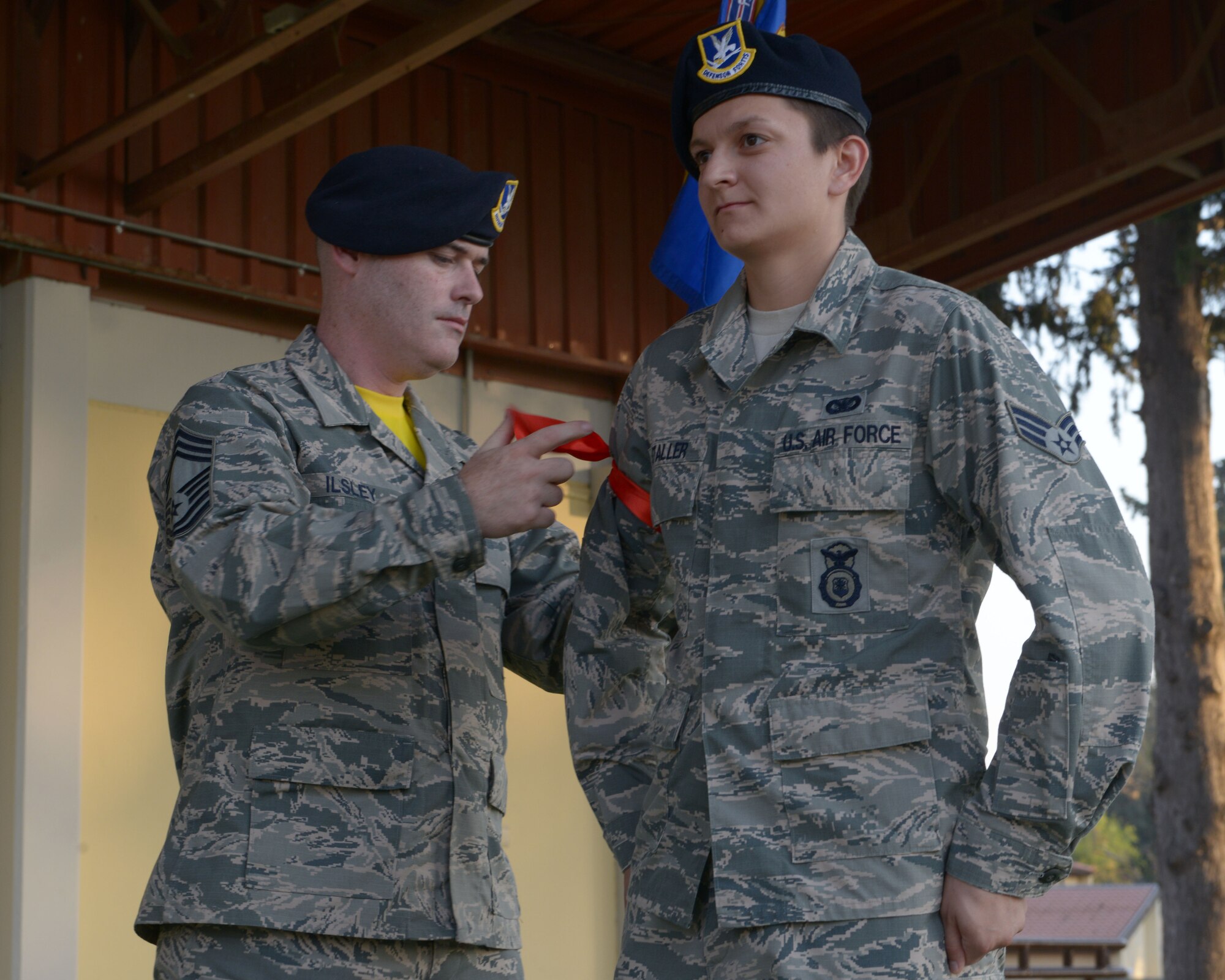 Chief Master Sgt. Joseph Ilsley, 39th Security Forces Squadron security forces manager, ties a red ribbon around the arm of Senior Airman Nicole Staller, 39th SFS base defense operations center controller, during a Bridge Ceremony Aug. 28, 2015, at Incirlik Air Base, Turkey. The ribbon represented the insignia used to distinguish NCOs during the revolutionary war. (U.S. Air Force photo by Senior Airman Krystal Ardrey/Released)