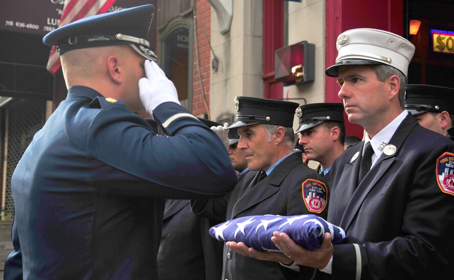Maj. Maj. Ryan VanVeelen, United States Air Force Honor Guard director of operations salutes leadership from New York City Fire Department Squad Company 1 after presenting the squad with an American flag on Sept.11, 2015 in New York City, N.Y.  Before presenting the squad with the flag, they joined them in a moment of silence at 8:46 a.m., the same time the first plane struck the North Tower of the World Trade Center buildings. (U.S. Air Force courtesy photo/Airman 1st Class Latasia Gross)