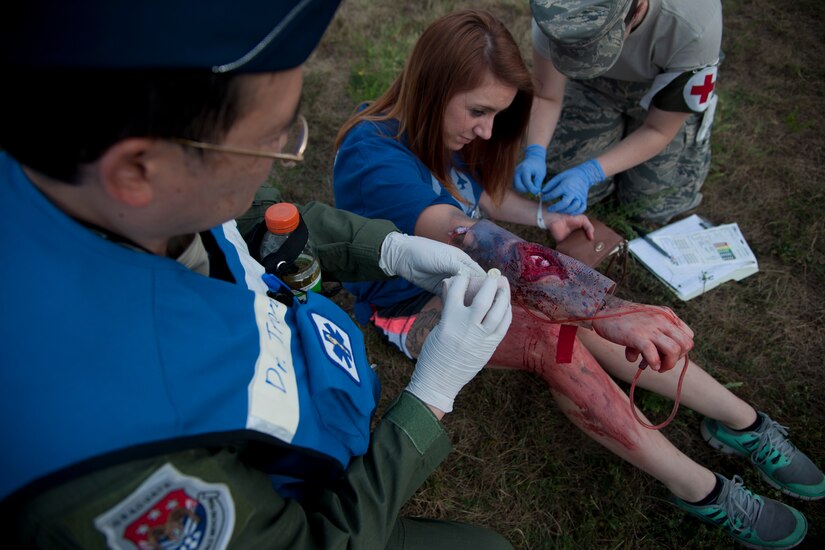 Col. Dai Tran, 779th Flight Medicine doctor, treats Lacey McGee, 811th Operations Support Squadron flight equipment technician, for simulated wounds at Joint Base Andrews, Md., Sept. 10 2015. The exercise tested a variety of preparedness aspects including first response and transporting patients to ambulances and helicopters. (U.S. Air Force photo/ Airman 1st Class J.D. Maidens/released)