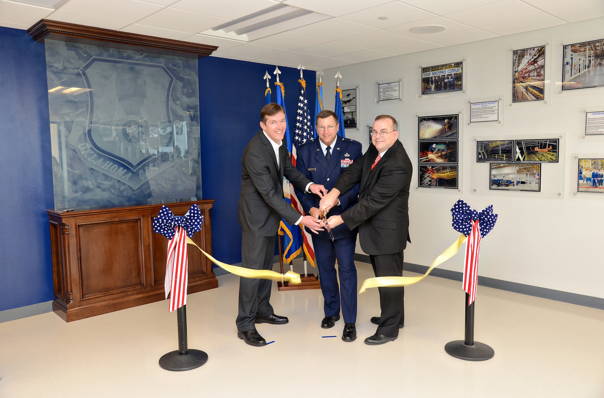 With the help of Oklahoma City Air Logistics Complex Vice Director Kevin O’Connor, left, and 76th Software Maintenance Group Director Michael Jennings, OC-ALC Commander Brig. Gen. Mark Johnson cuts the ribbon to officially open the 76th SMXG’s new administration area in Bldg. 9001. “This is a great opportunity to celebrate something we don’t normally get to do, and that is open a new facility,” General Johnson said. “It all started with people who had a vision, foresight and perseverance. It goes back a long time when we asked what we could do for the future and managing the opportunity for growth.” The software group was started in 1983 with just 30 employees and now has more than 800 engineers. “You all generated $163 million in revenue last year,” the general said. “We could hire every engineer coming out of the Oklahoma higher education system and it wouldn’t be enough for where we need to be in the future. The growth is absolutely phenomenal.” He added that giving the employees a comfortable place to work is the least they can do to ensure continued success.  (Air Force photo by Kelly White)