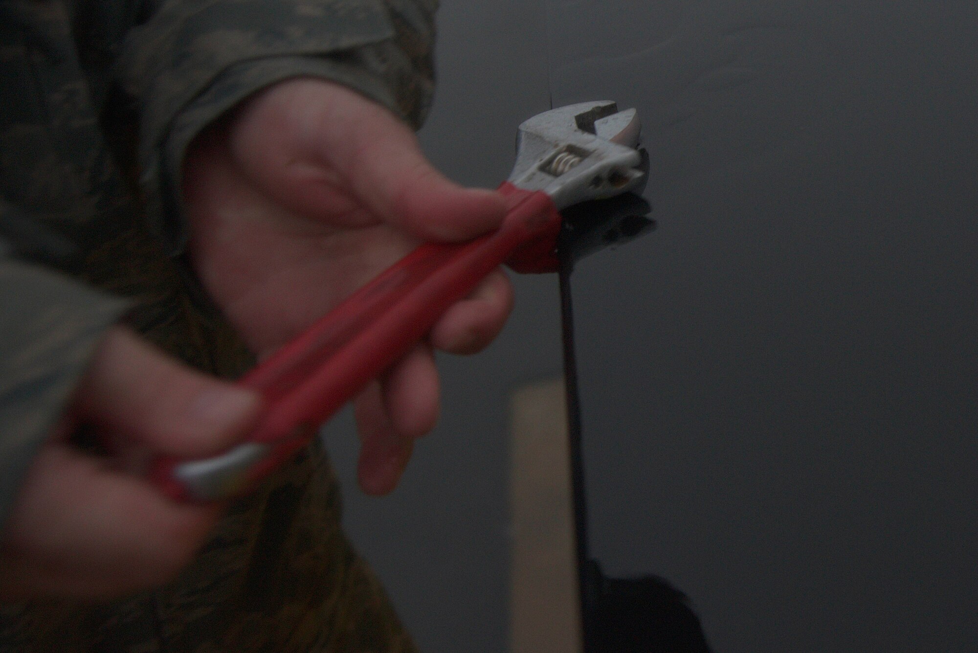 An electrical systems Airman from the 35th Civil Engineer Squadron untightens a bolt on a light panel at Misawa Air Base, Japan, Sept. 11, 2015. The Airmen removed lights on the edge-way of the flightline to prepare for the arrival of a B-52H Stratofortress, which has a wingspan long enough to potentially hit lights during landing. (U.S. Air Force photo by Senior Airman Jose L. Hernandez-Domitilo/Released)